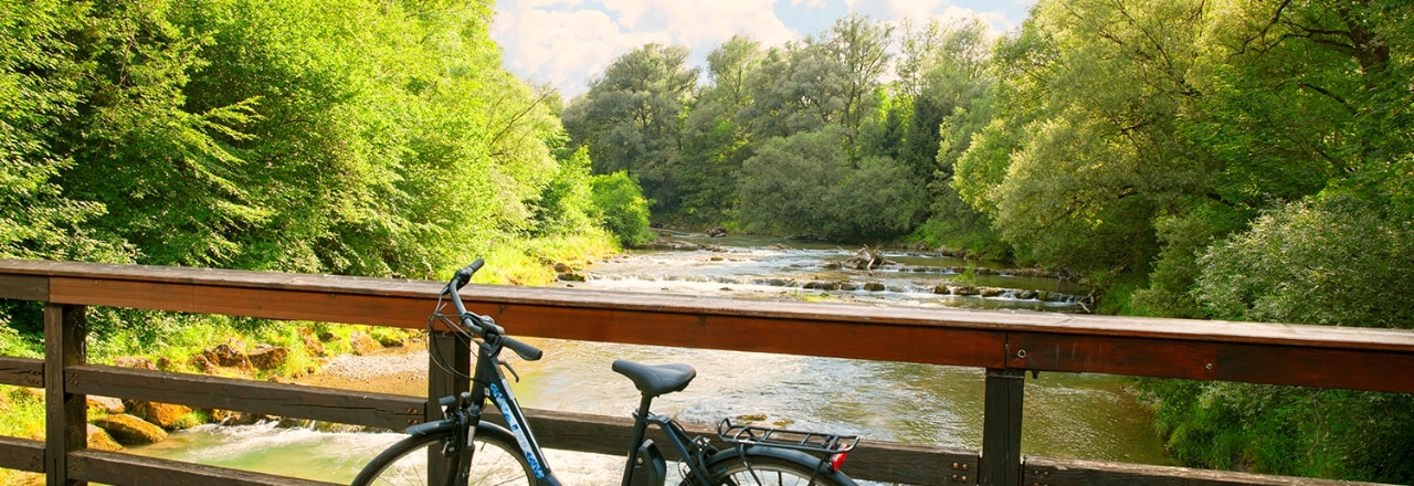 Ein schwarzes Fahrrad steht auf einer Brücke über einen Fluss