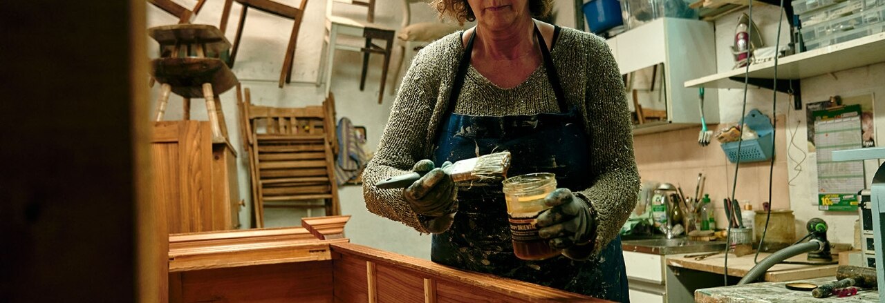 Eine Frau restauriert ein Möbelstück