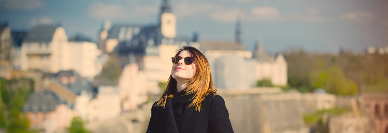 Junge Frau mit Sonnenbrille genießt die Sonne in Luxemburg