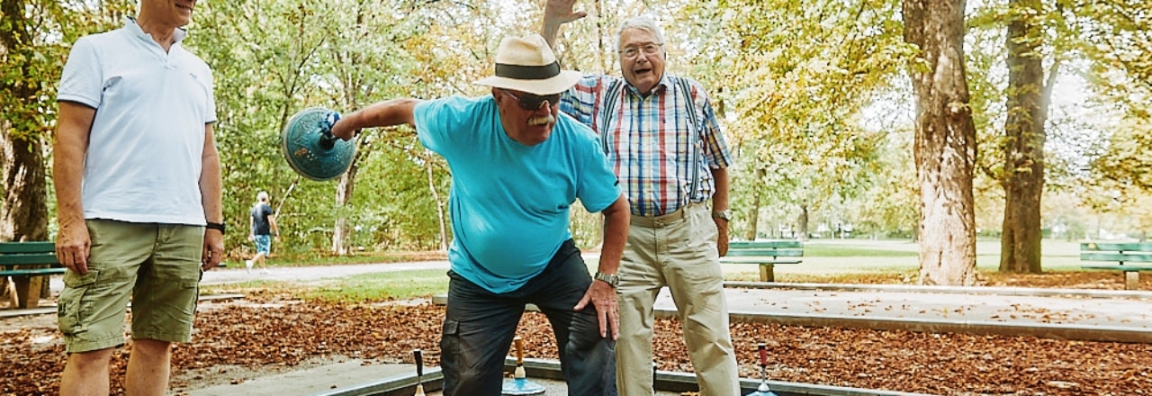 Drei Senioren beim Stockschießen im Park