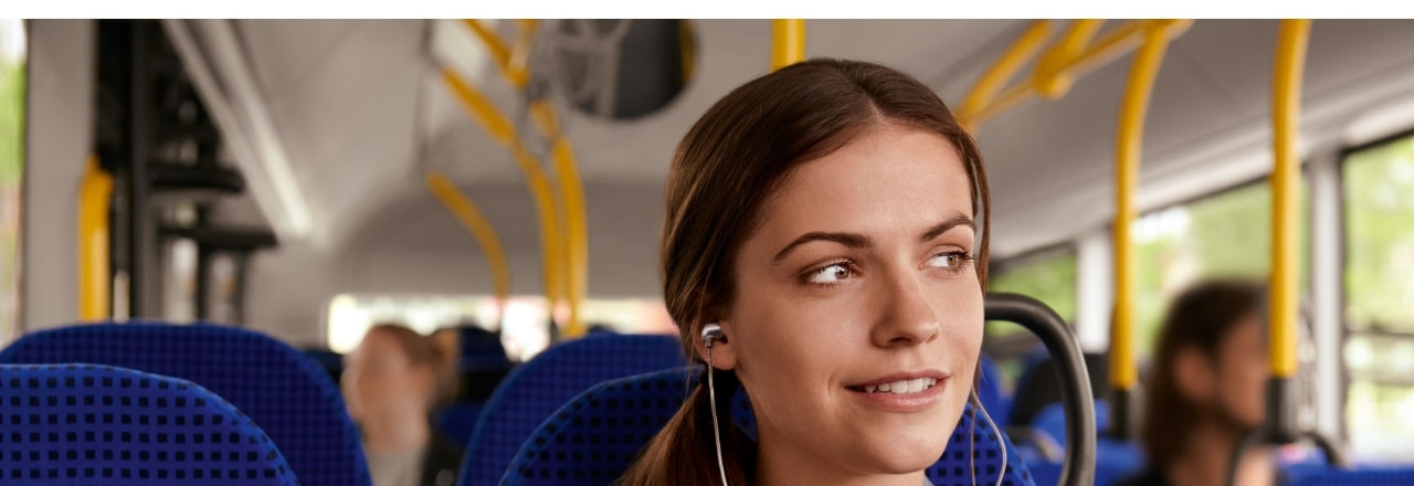 junge Frau mit Ohrstöpseln im Bus