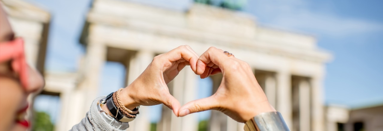 Schmuckbild - Frau vor Brandenburger Tor in Berlin formt Herz mit ihren Händen.