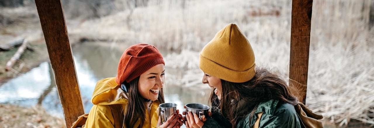 Zwei Frauen halten jeweils eine Tasse in der Hand und lachen gemeinsam