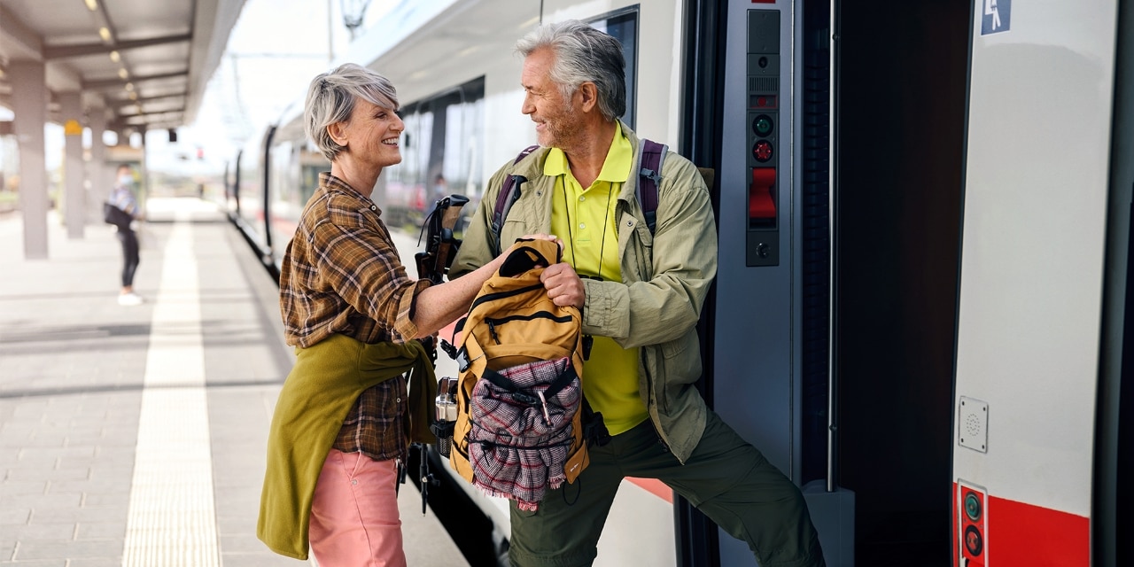 Senioren mit Alltags-Outfit steigen in einen Zug ein