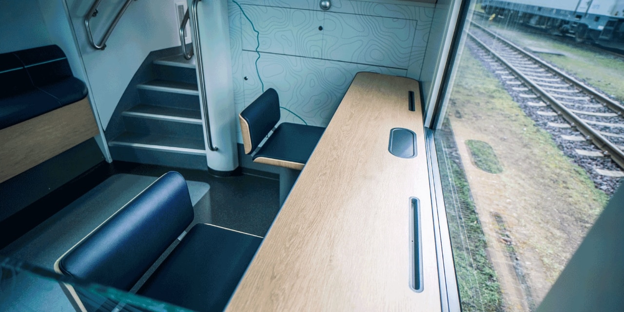 Eine Arbeitstheke am Fenster mit Tablethalterung, zwei Stehhockern und beleuchteten Steckdosen ermöglicht das schnelle Arbeiten von unterwegs.