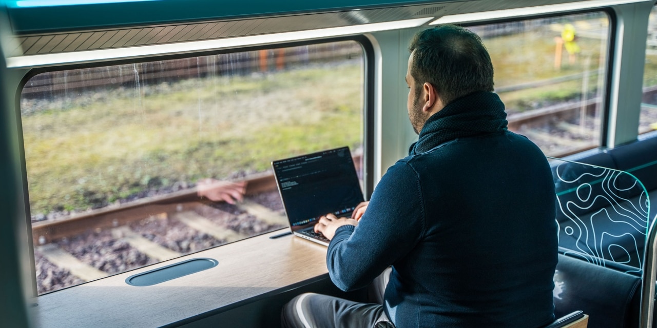 Eine Arbeitstheke am Fenster mit Tablethalterung, zwei Stehhockern und beleuchteten Steckdosen ermöglicht das schnelle Arbeiten von unterwegs.