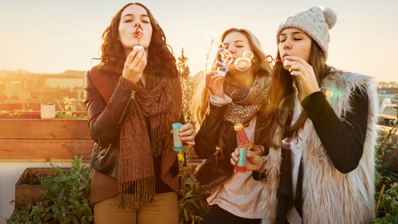 Drei junge Frauen machen Seifenblasen
