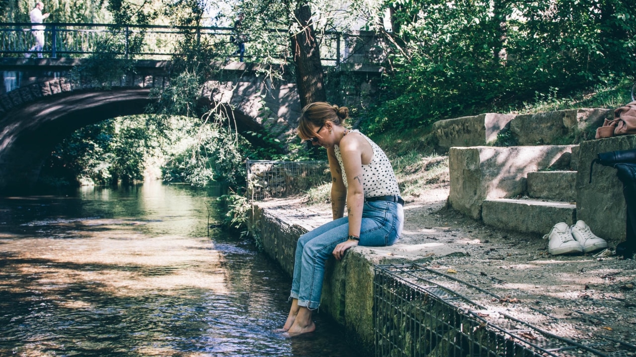 Frau sitzt an einem Fluss