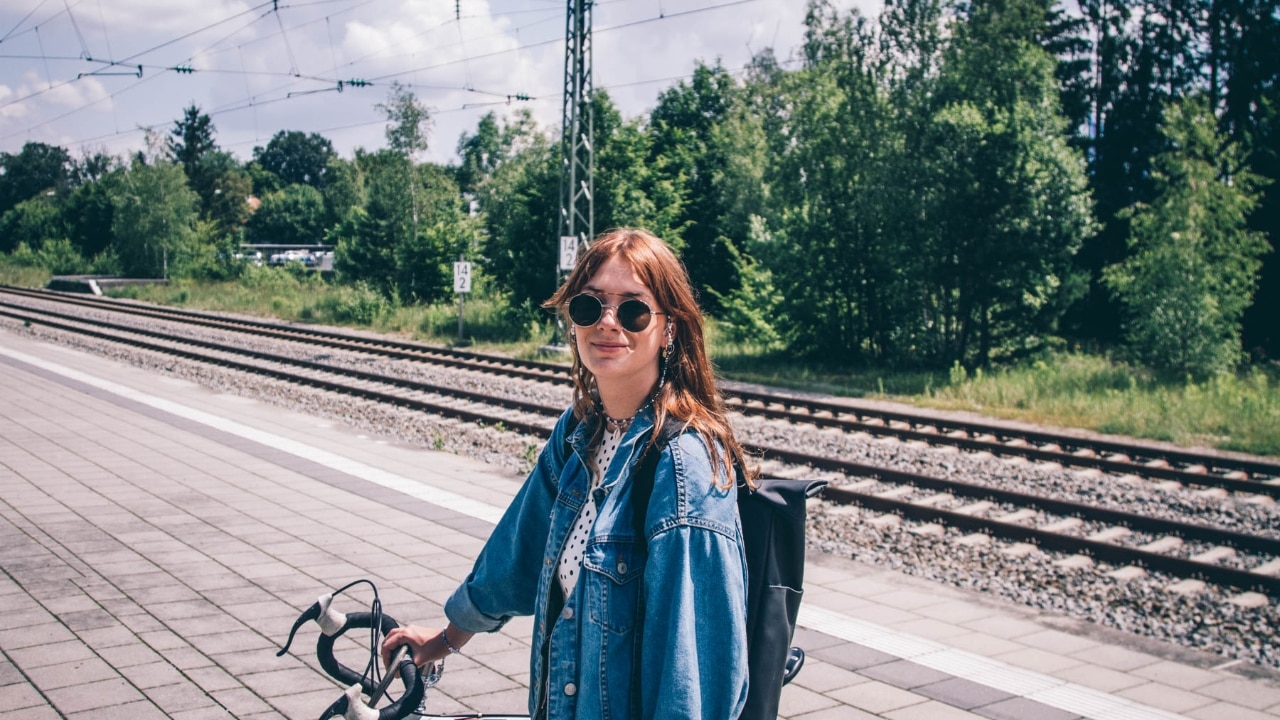 Frau steht mit Fahrrad an S-Bahn Station