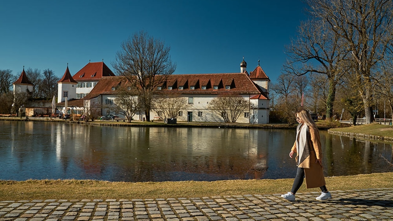 Frau geht vor Schloss Blutenburg spazieren