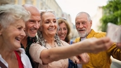 Group of happy senior friends tourists on a walk in city, taking selfie.