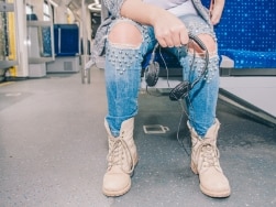 Person in der S-Bahn hält Kopfhörer in den Händen