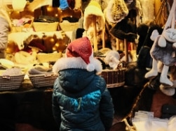 Kind mit Weihnachtsmannmütze vor Mützenladen
