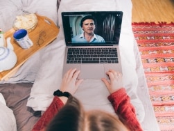 Person schaut eine Serie auf ihrem Laptop im Bett