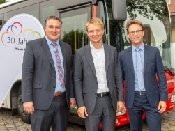 Arne Schneemann, Jan Enzensberger und Jörg Schneider vor 30-Jahre Weser-Ems-Bus-Flagge und rotem Bus