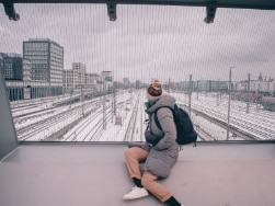 Person sitzt auf dem Arnulfsteg und schaut auf die darunterliegenden Gleise
