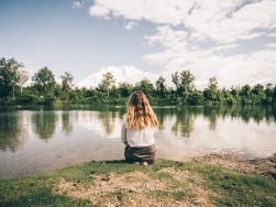 Person sitzt an einem See