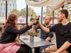 Drei Leute stoßen mit Bierflaschen an