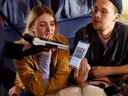 Junges Paar zeigt Ticket auf Handy bei Fahrkartenkontrolle