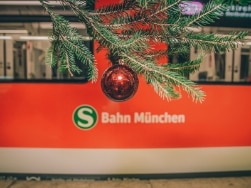 Christbaumkugel an einem Tannenzweig vor einem Zug der S-Bahn München