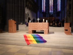Regenbogenflagge liegt in Kirche vor dem Altar