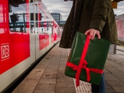 Frau mit einem Geschenk steht am Bahnsteig vor der S-Bahn