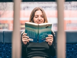 Frau sitzt lesend in der S-Bahn