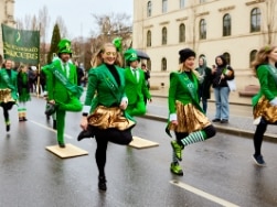 Grün gekleidete Frauen und Männer tanzen auf einer Straße