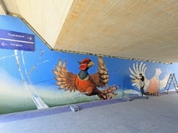 Mann sprüht Graffiti von Fasanen an die Wand einer S-Bahnstation 