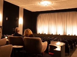Mann und Frau auf Sesseln sitzend in einem Kinosaal