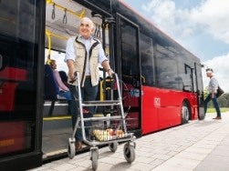 Senior steigt mit Rollator hinten aus Bus aus