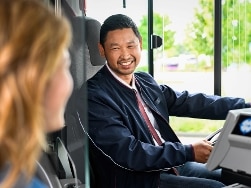 Busfahrer lächelt und Frau steigt in den Bus ein