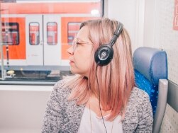Frau mit Kopfhörern sitzt in der S-Bahn