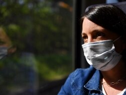 Frau mit medizinischer Maske am Fenster