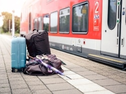 Gepäck am Bahnsteig, Regio-Zug im Hintergrund