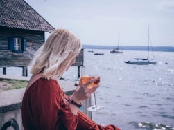 Frau mit Getränk am Ufer des Ammersees