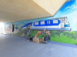 Mann sprüht ein S-Bahn Graffiti an die Wand einer S-Bahnstation