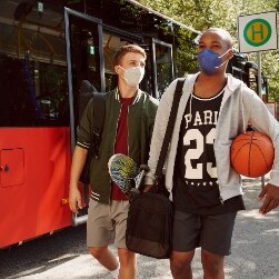 Junge Männer mit Basketbällen vor Bus
