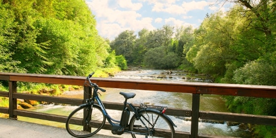Ein schwarzes Fahrrad steht auf einer Brücke über einen Fluss