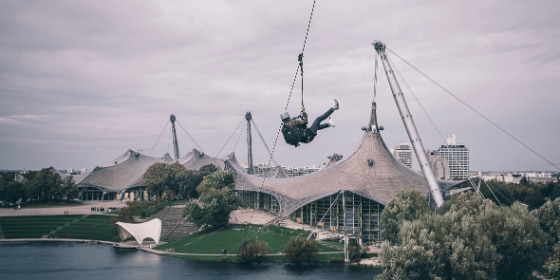 Person fliegt mit dem Flying Fox über den Olympiasee München