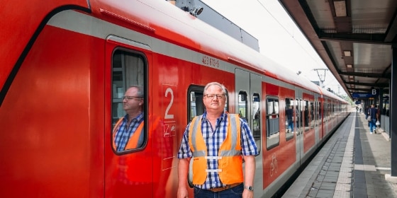 Mitarbeitender der Baustellenkommunikation neben einer S-Bahn