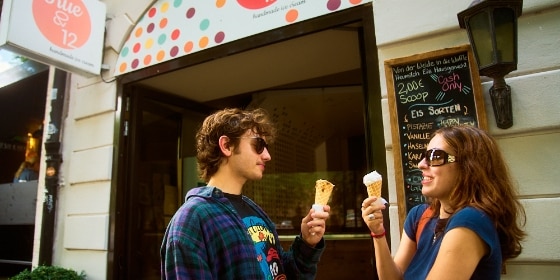 Mann und Frau stehen vor einer Eisdiele und essen Eis