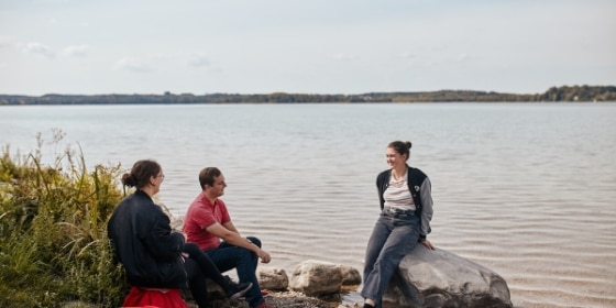 Drei Leute sitzen am Ufer des Wörthsees