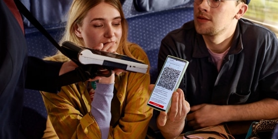 Junges Paar zeigt Ticket auf Handy bei Fahrkartenkontrolle