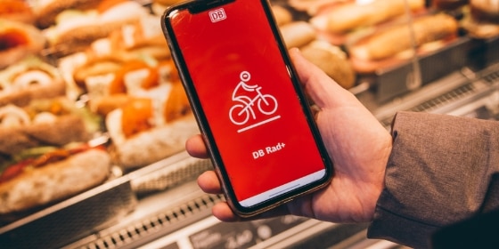 Person hält ein Handy mit der DB Rad+ App in der Hand