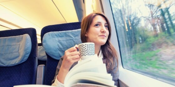 A young woman drinking coffee inside a running train