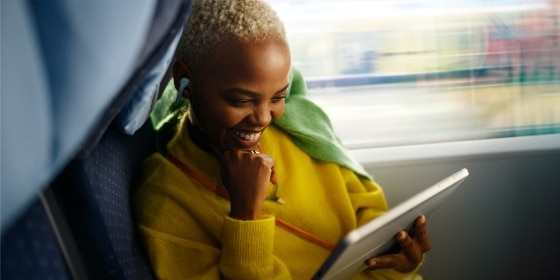 Frau entspannt im Zug, blickt auf ein Tablet.