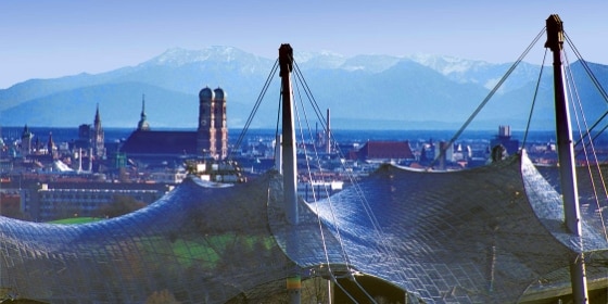 Blick über das Olympiazelt-Dach auf München und die Berge