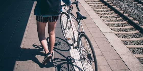 Person schiebt ihr Rad den Bahnsteig entlang