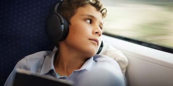 Junge mit Kopfhörern blickt aus dem Zug